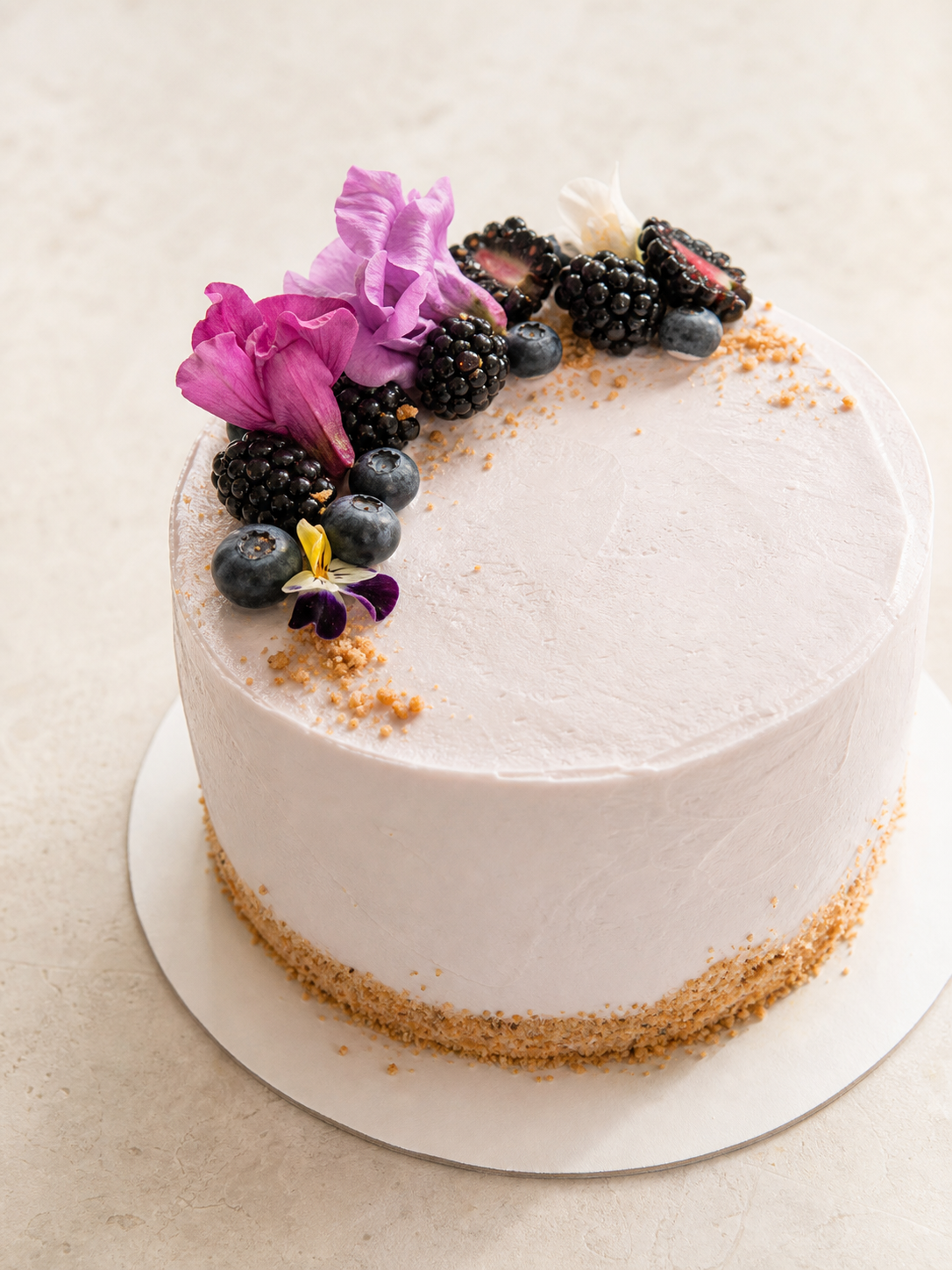 Pistachio cake with vanilla buttercream, berries, and flowers