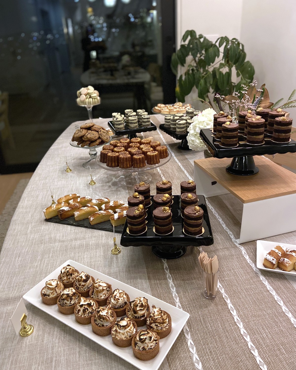 Event dessert table with layered cakes, cookies, caneles, and tartlets