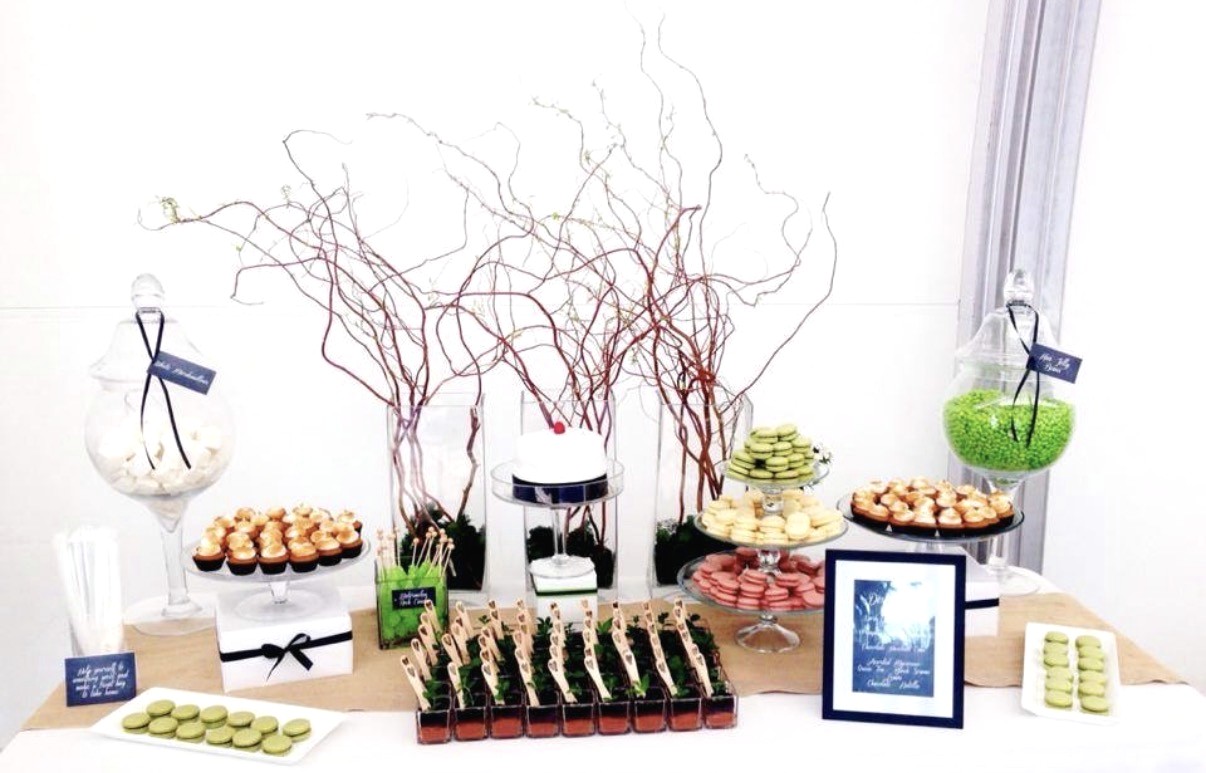 Dessert table with macarons, small bites, branches, and glass vessels